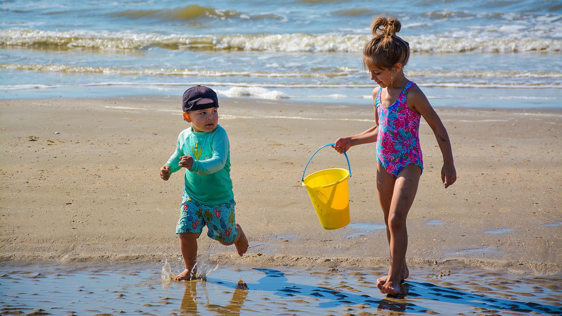 Kids walking on beach with sand bucket